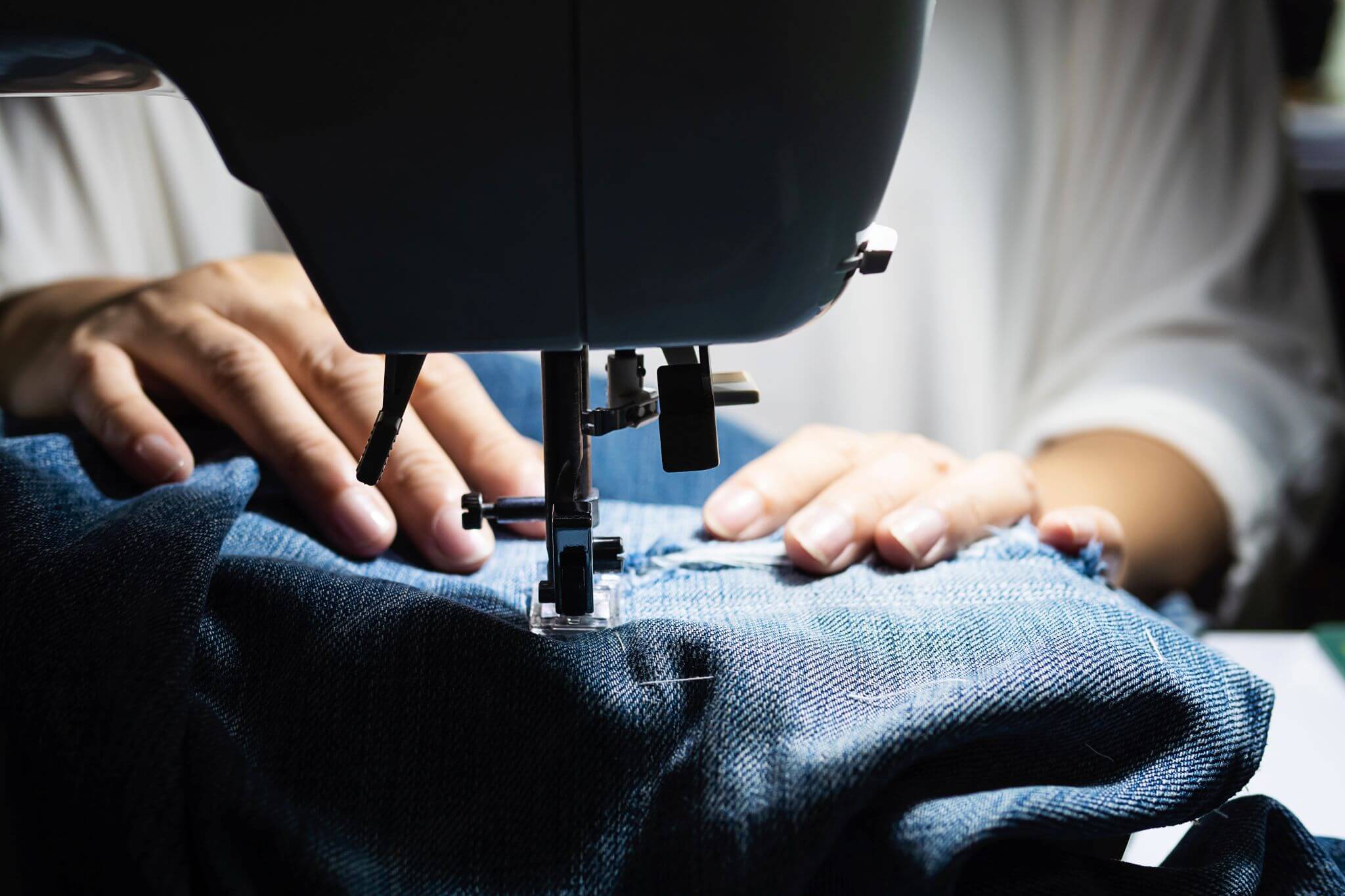 woman-doing-jeans-patchwork-using-sewing-machine-home-diy-sewing-concept